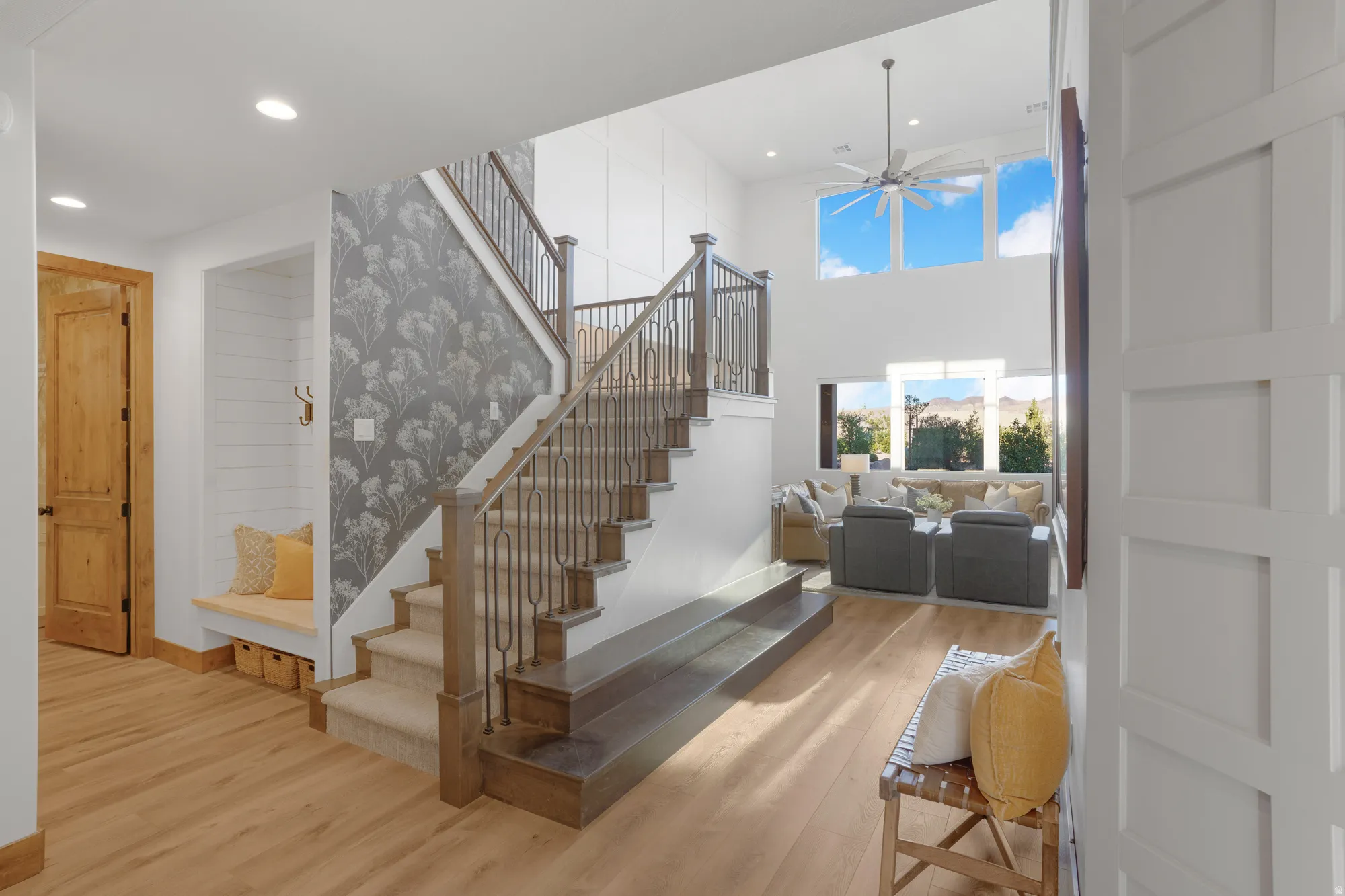 Hardwood flooring throughout, a custom built-in bench, and a two-story ceiling with a ceiling fan