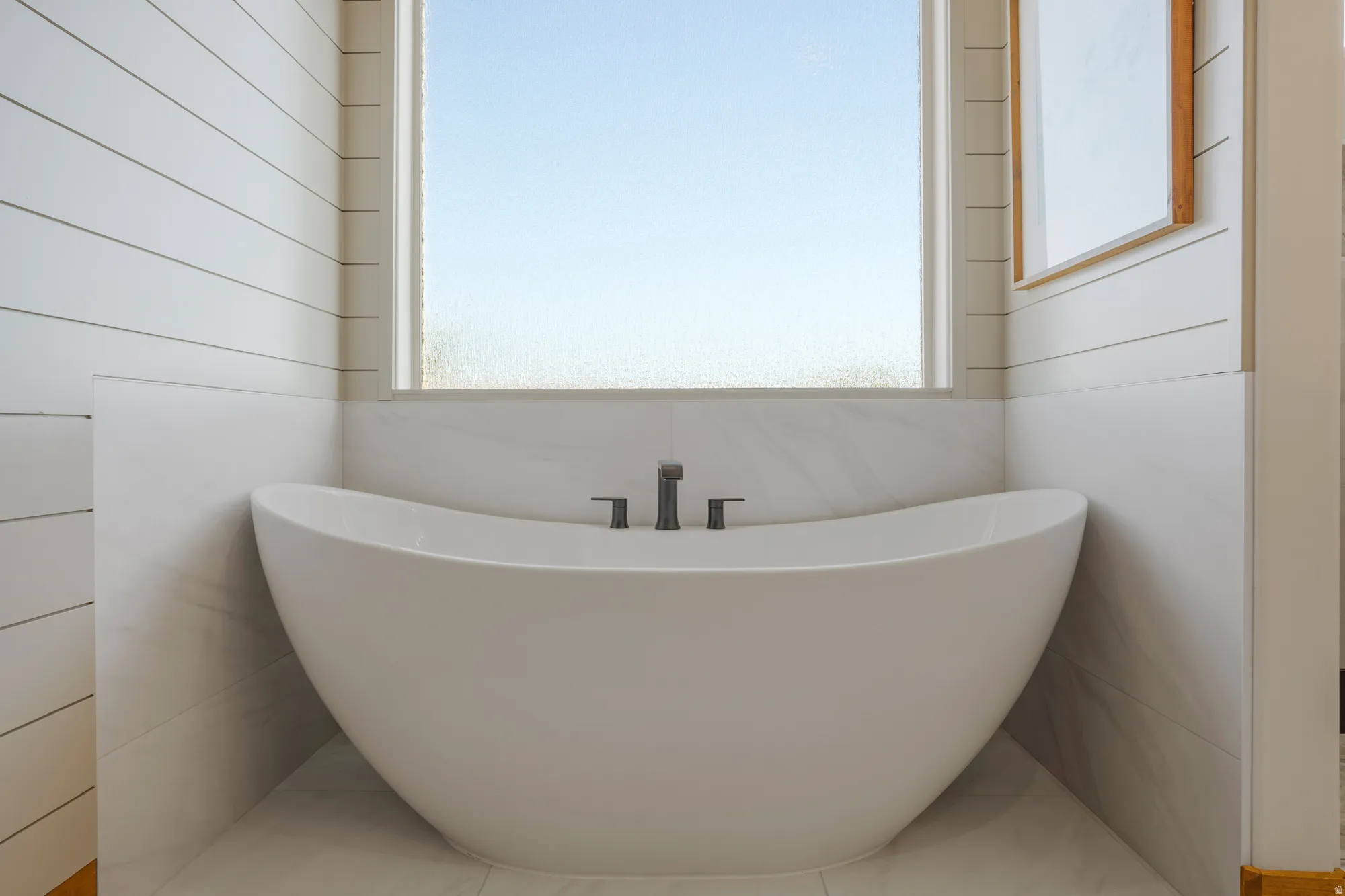 Freestanding soaking tub with dark-toned fixtures
