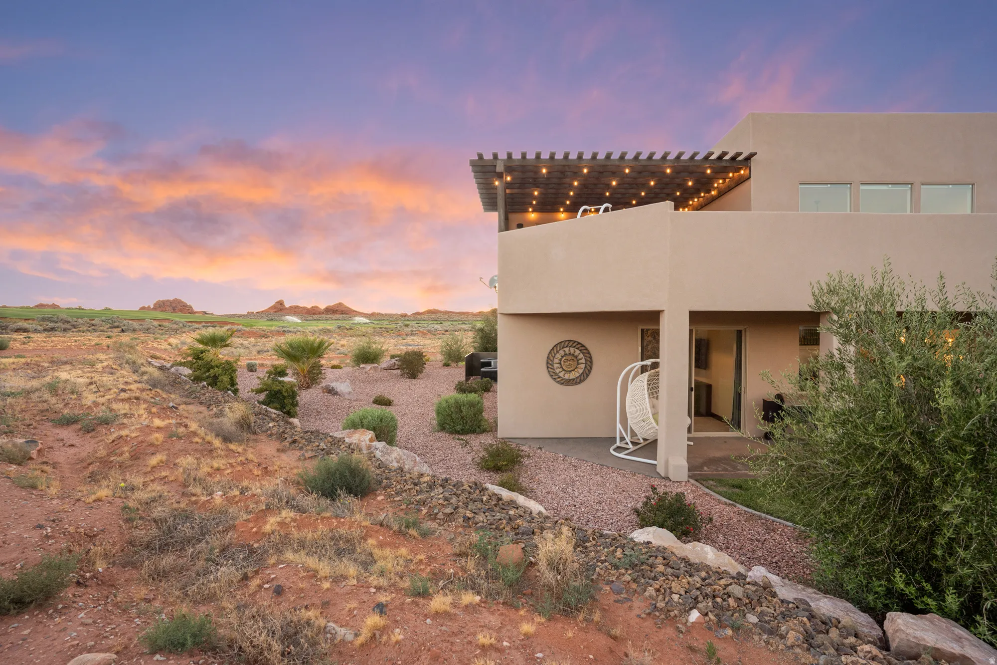 Terraced outdoor space with a gravel patio, covered entry, and a second-story balcony with a pergola