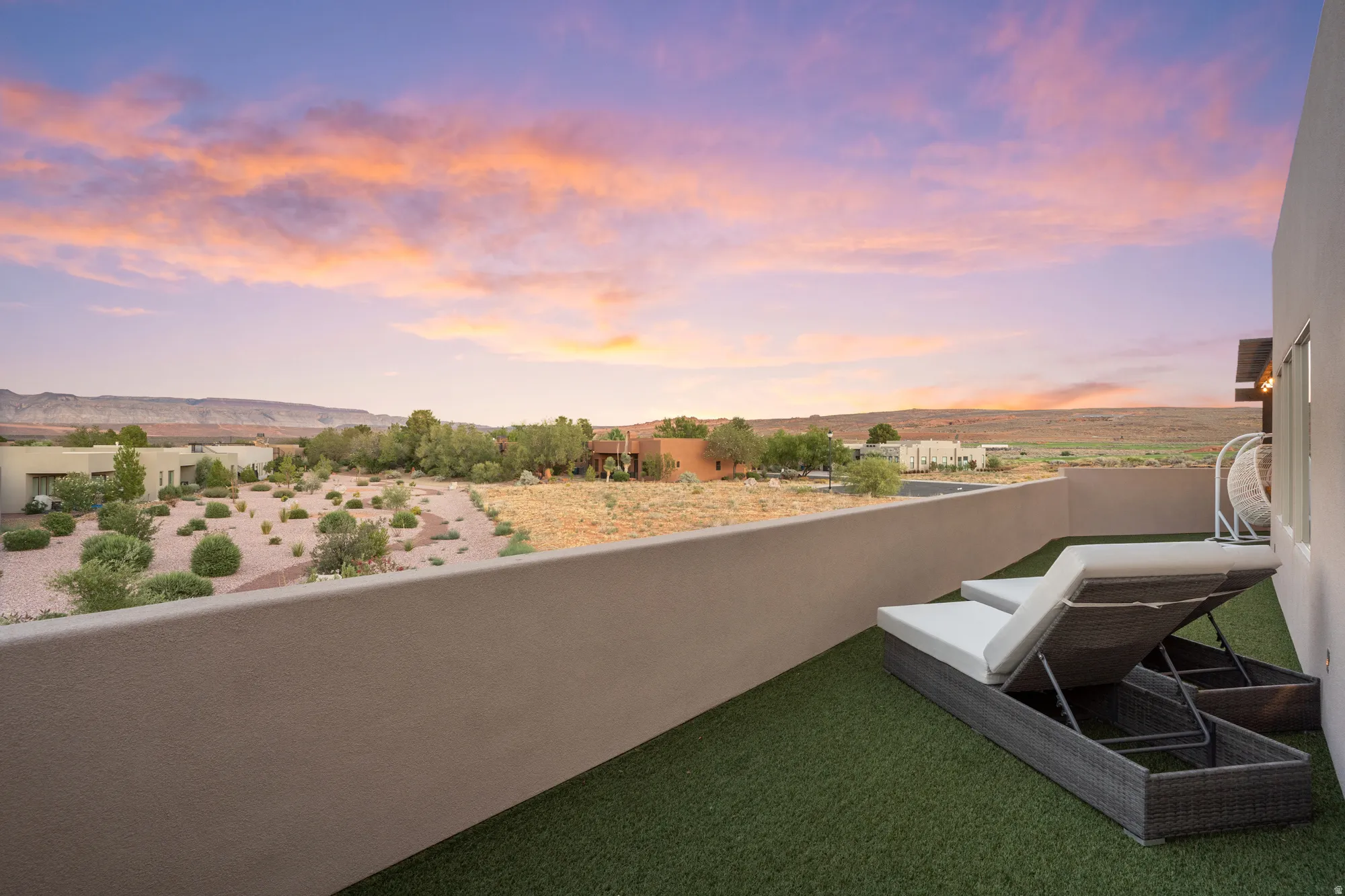Rooftop deck featuring artificial turf, a privacy wall, and expansive desert landscape