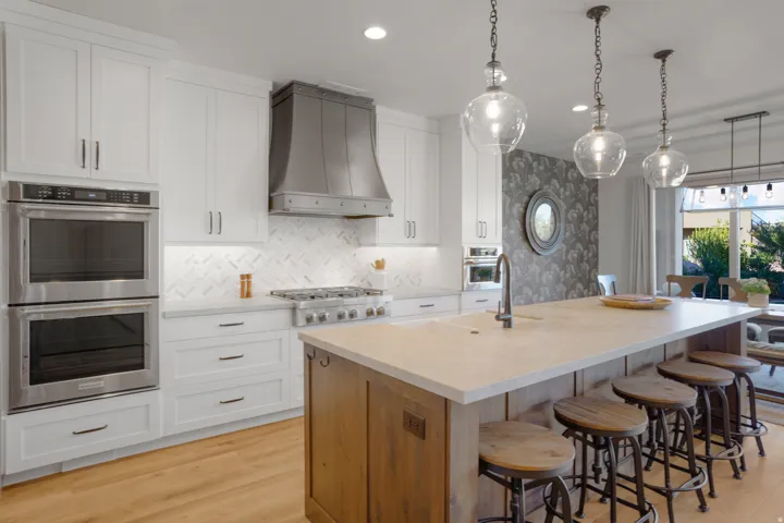 Gourmet kitchen featuring a large island with seating, double wall ovens, a professional range, and a decorative range hood