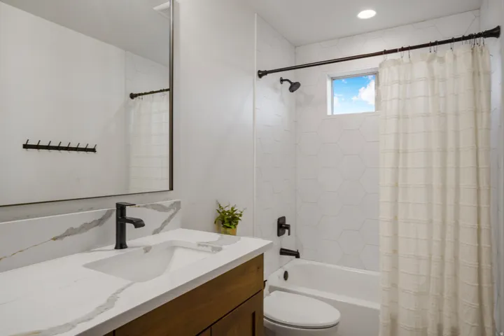 Bathroom featuring a single vanity with stone-finish countertop, matte black faucet, and rectangular undermount sink