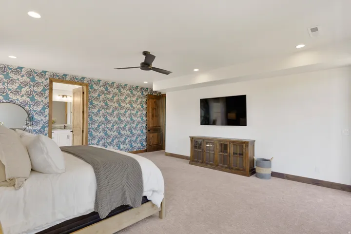 Recessed lighting, ceiling fan, accent wall with patterned wallpaper, wood-finish doors, and plush carpeting