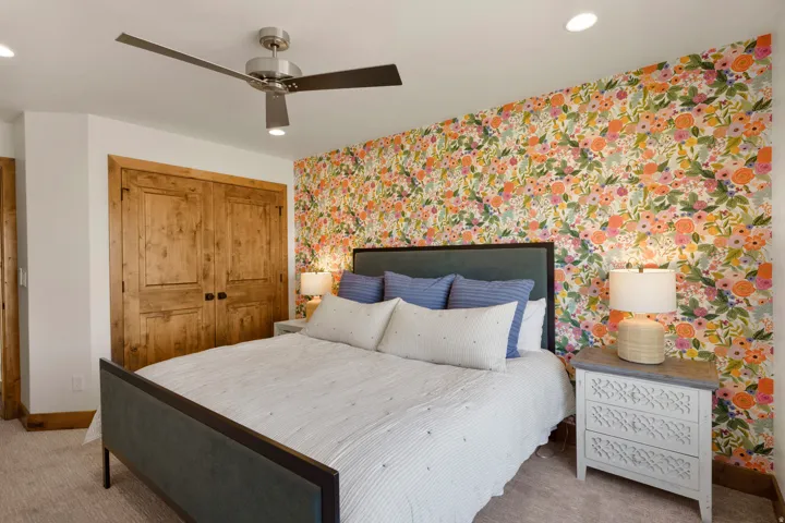 Floral accent wall, wood-finish bi-fold closet doors, recessed lighting, ceiling fan, and carpeted flooring