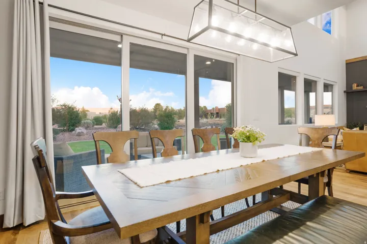 Spacious interior with high ceilings, wood-finish flooring, and a contemporary linear chandelier