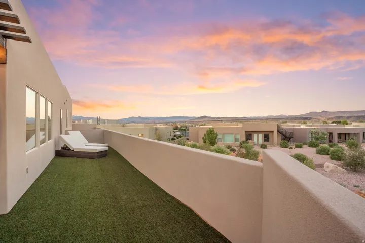 Rooftop deck featuring artificial turf, plaster walls, and a glass safety barrier