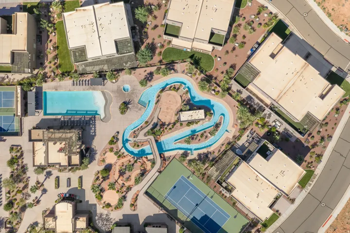 Expansive recreational area featuring a large swimming pool, circular spa, winding lazy river, and two tennis courts