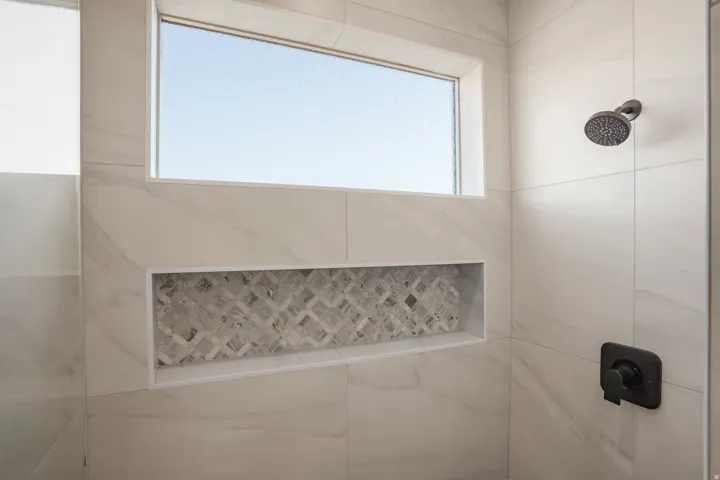 Tiled shower with a niche featuring mosaic tile