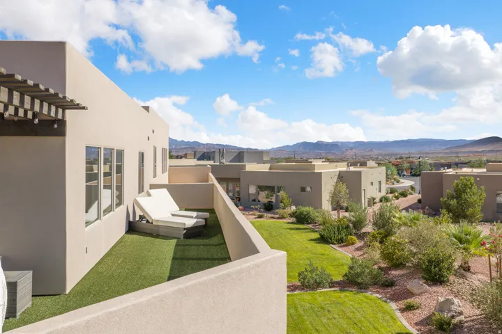 Terrace with artificial turf, stucco exterior, multiple windows, and a pergola structure