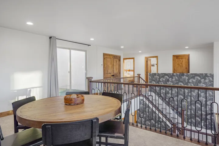 Loft area featuring a sliding glass door, recessed lighting, wood-finish doors, and an iron baluster railing