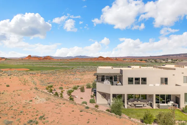 Contemporary exterior with multiple balconies and patios, featuring a desert landscape with distant red rock formations and a green expanse