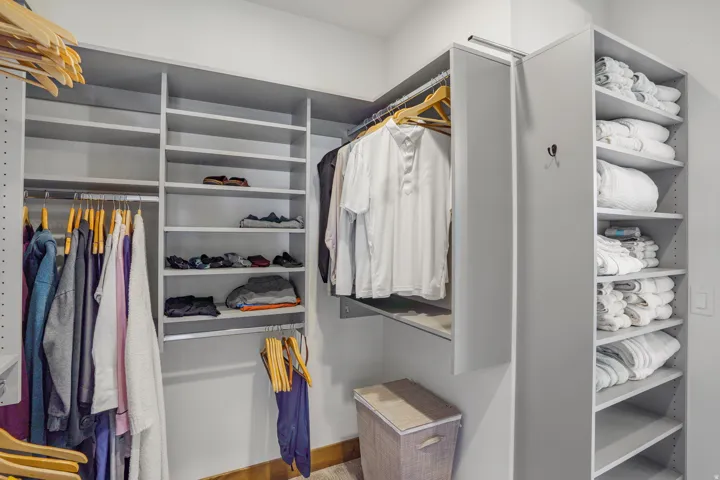 Custom closet system featuring multiple shelving units, integrated hanging rods, and a tall storage tower with adjustable shelves