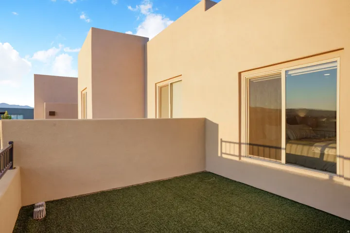 Stucco exterior with a private outdoor space, featuring artificial turf and a metal railing