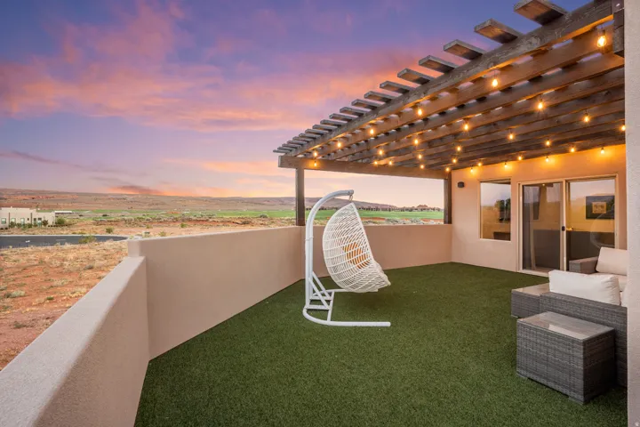 Terrace featuring a wood pergola with string lighting, simulated turf flooring, and a stucco perimeter wall