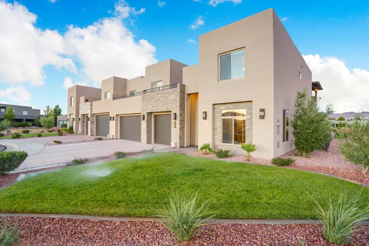 Modern stucco exterior with stone accents, multiple garages, and a second-story balcony
