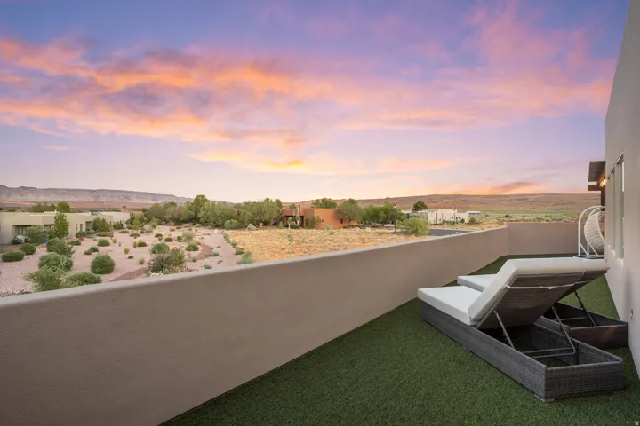 Rooftop deck featuring artificial turf, a privacy wall, and expansive desert landscape