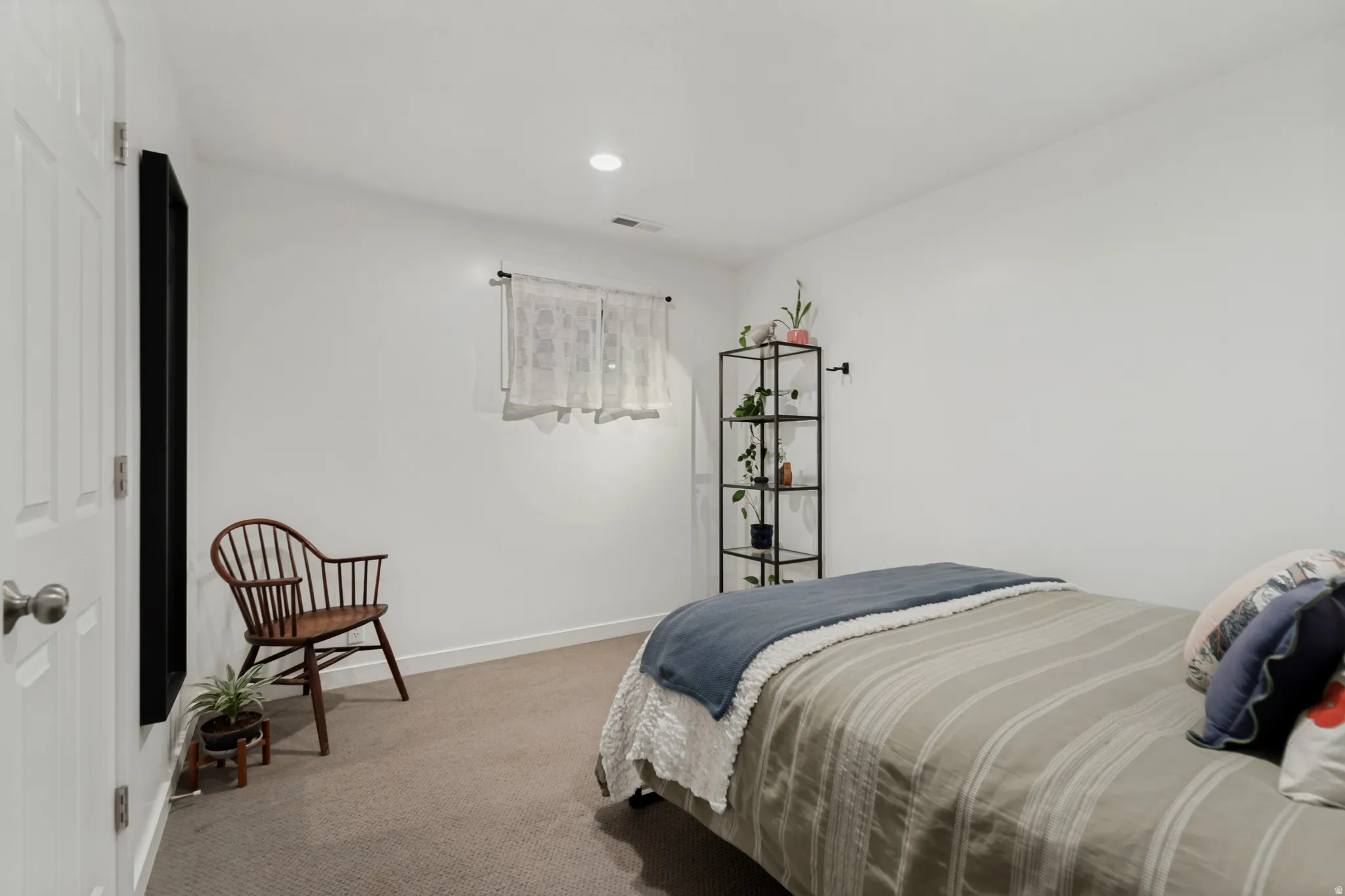 Recessed ceiling lighting, white interior door, window with natural light, carpeted flooring, and crisp white walls