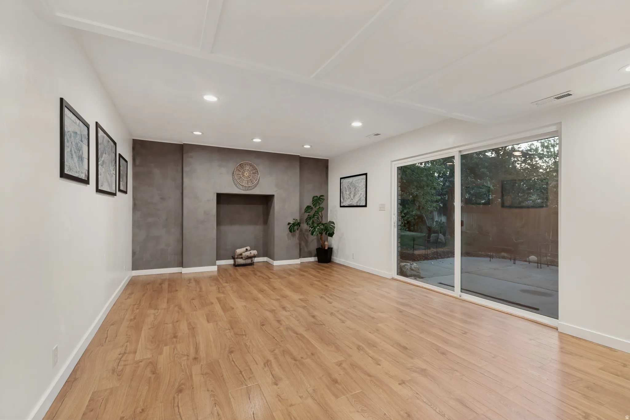Recessed lighting, wood-finish flooring, and a decorative fireplace niche, complemented by a sliding glass door