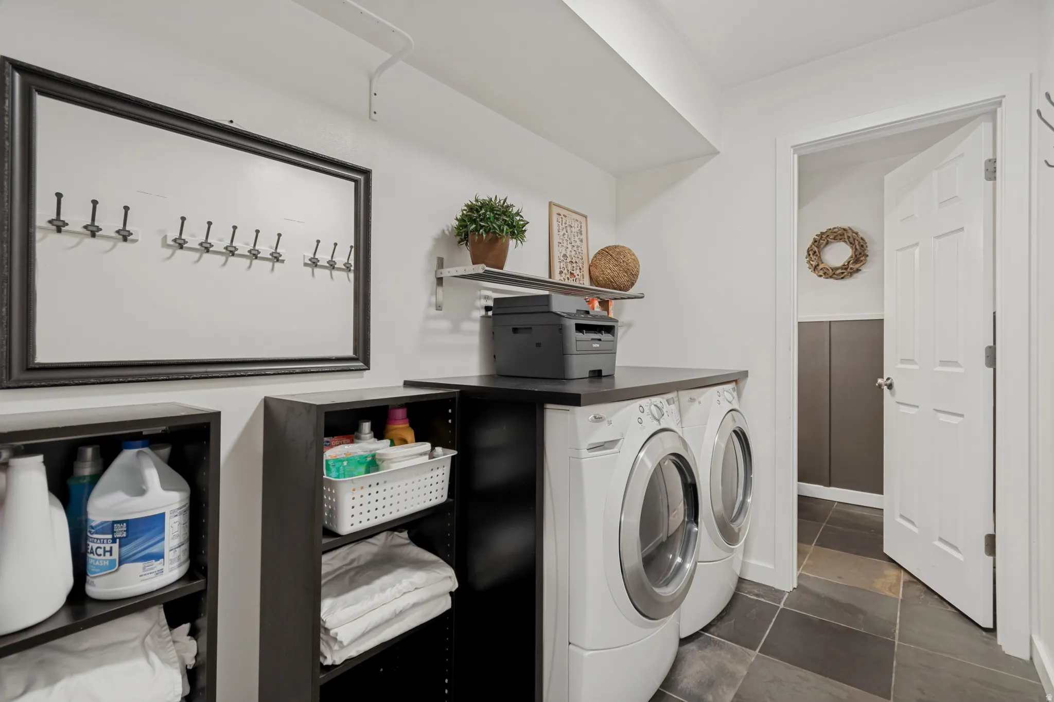Front-loading washer and dryer, dark countertop, built-in shelving, dark tile flooring, and a paneled door