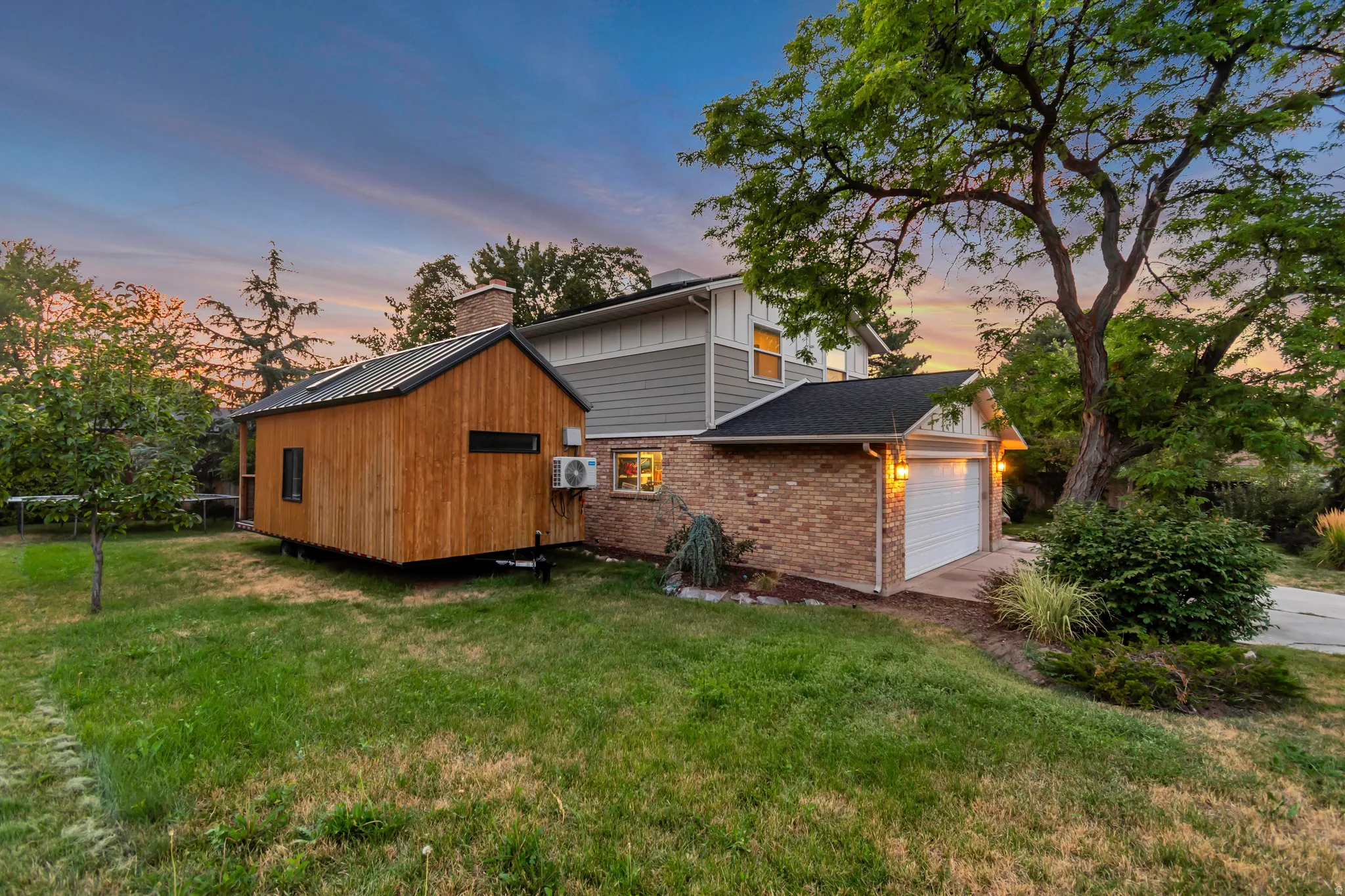 Brick and siding exterior with an attached garage, featuring a separate wooden structure with a metal roof