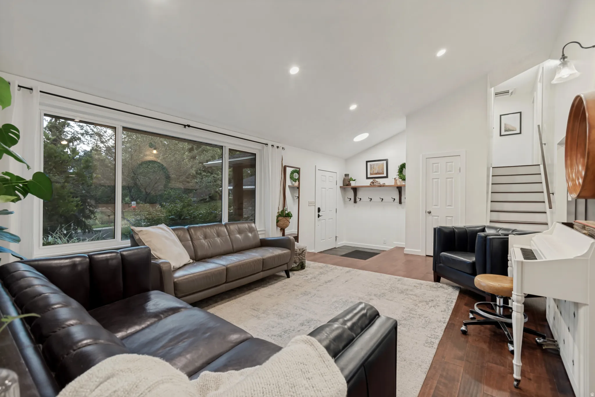 Bright living space featuring recessed lighting, a vaulted ceiling, wood-finish flooring, and a large picture window