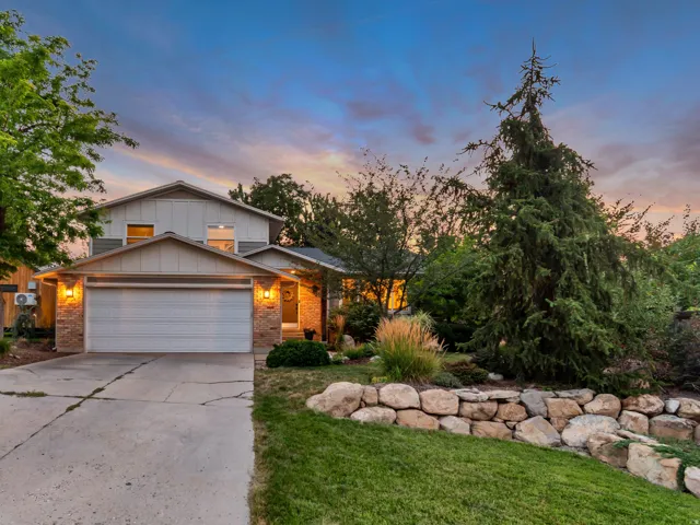 Two-story residence featuring a two-car garage, stone facade accents, and mature landscaping