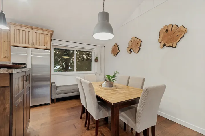 Hardwood flooring, stainless steel refrigerator, wood cabinetry, built-in lighting, and a multi-pane window