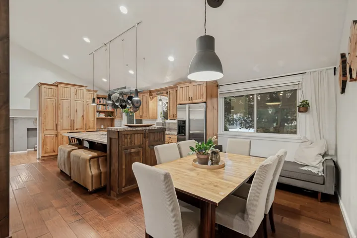 Vaulted ceilings, wood-finish flooring, recessed lighting, wood cabinetry, and a central island with integrated seating