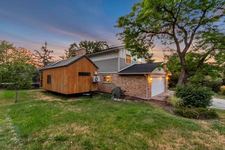 Brick and siding exterior with an attached garage, featuring a separate wooden structure with a metal roof