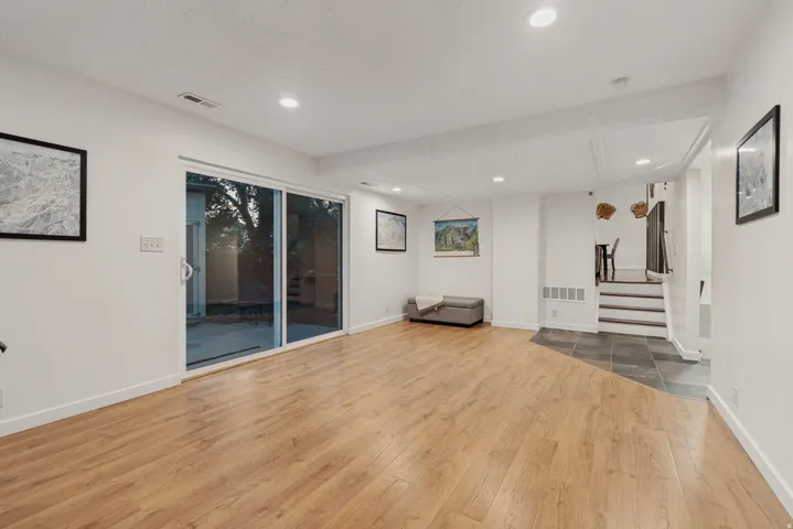 Wood-finish flooring with recessed lighting, sliding glass door, and a tiled entry