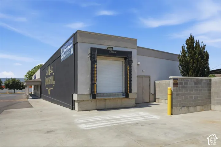 Commercial building with a loading dock, large roll-up door, and concrete block privacy wall