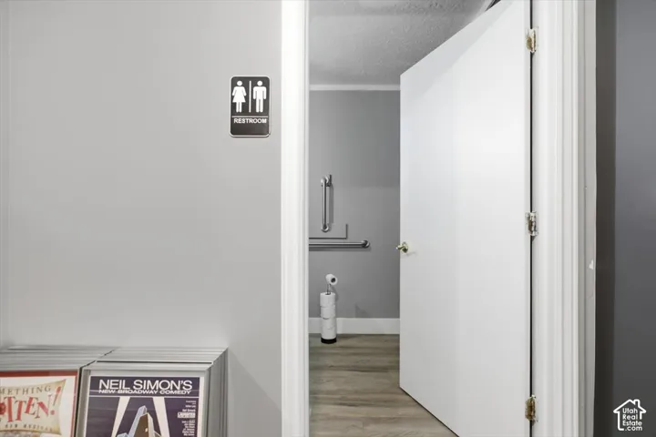 Modern bathroom entry featuring a clean, minimalist design with white-painted walls, wood-finish flooring, and a frameless glass shower enclosure