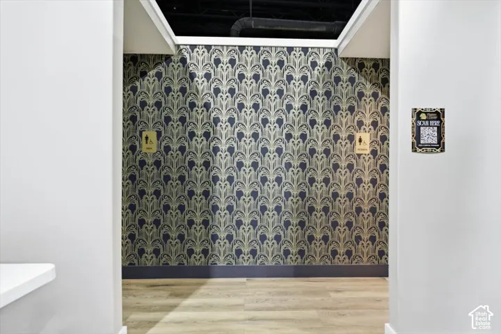 Patterned wallpaper, light wood-finish flooring, and white painted walls