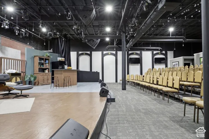 Exposed ceiling with track lighting, multiple-row seating, arched wall niches, brick accent wall, and built-in counter