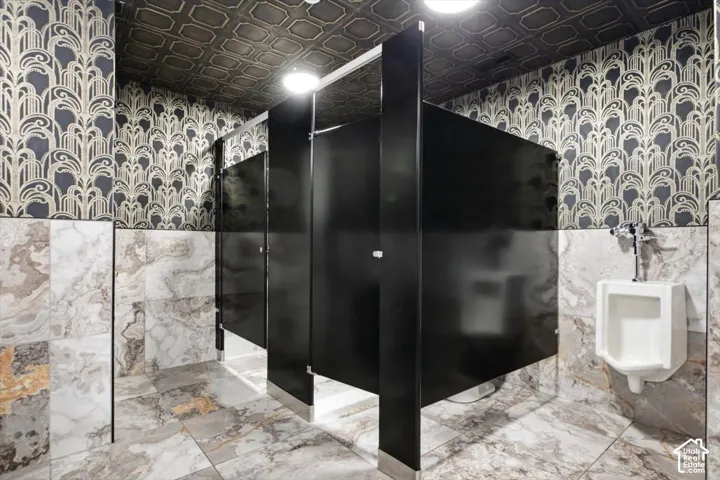 Patterned wallpaper, geometric ceiling panels, floor-to-ceiling wall tiling, and dark partition walls