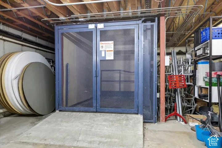 Industrial-style freight elevator with mesh doors, concrete ramp, and exposed ceiling joists
