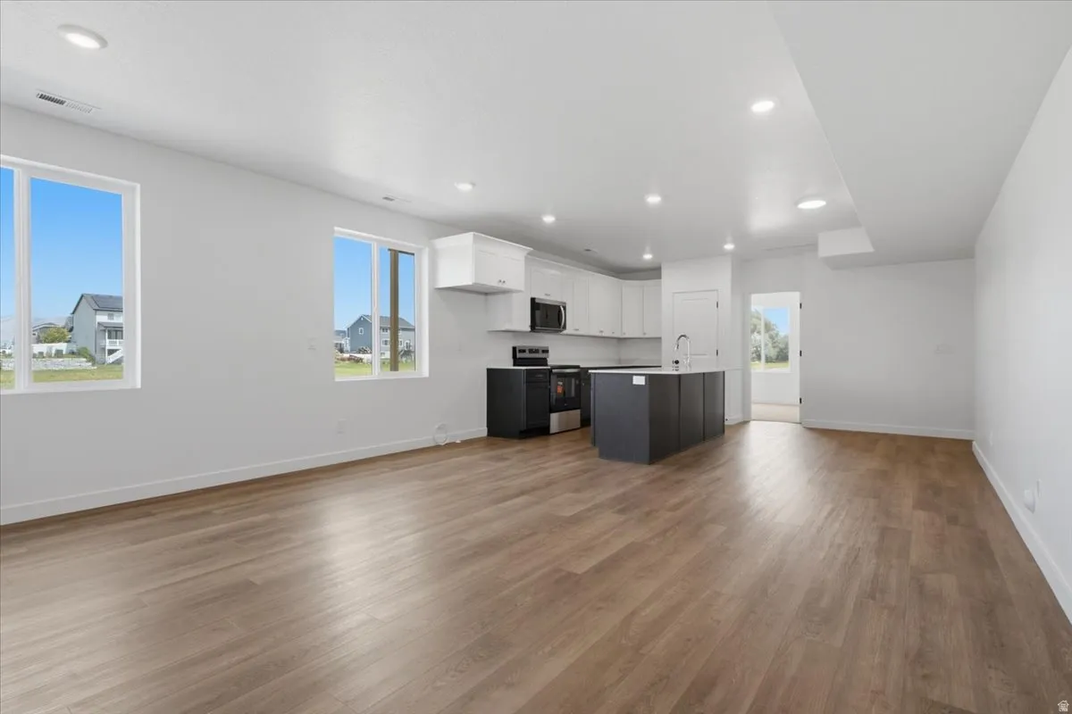 Open-concept living space featuring wood-finish flooring, recessed lighting, and multiple windows