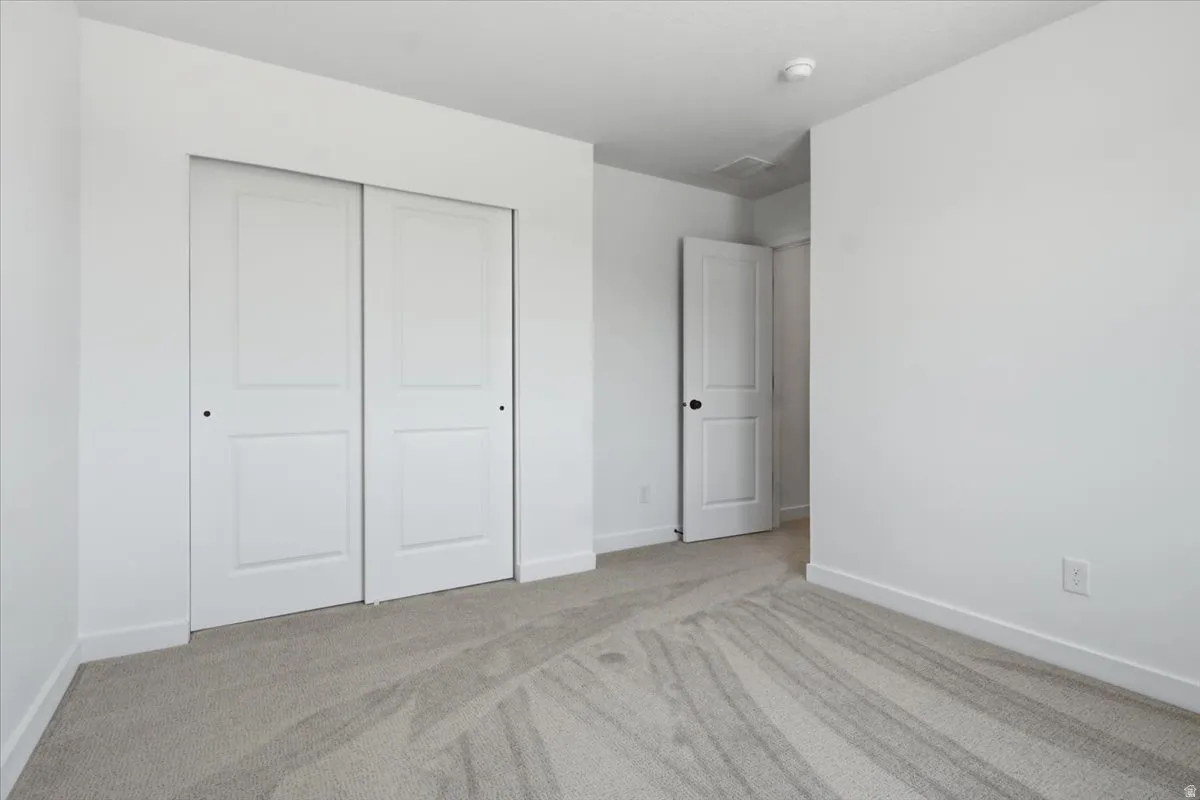 Wall-to-wall carpeting with light-toned walls, white trim, and a white sliding closet door