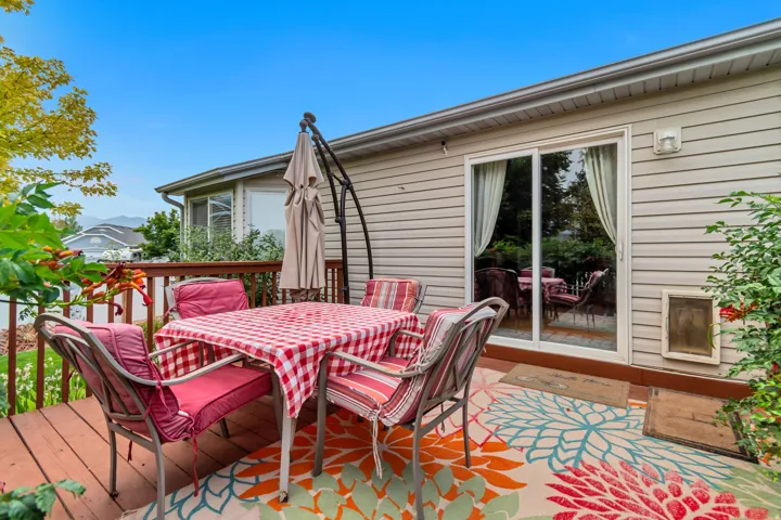 Expansive wooden deck with a sliding glass door entry and light-toned siding