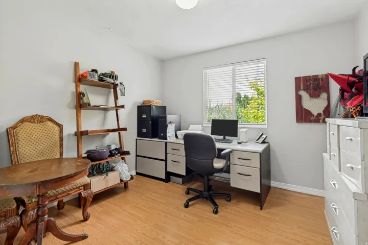 Window with blinds, wood-finish flooring, white walls, built-in desk