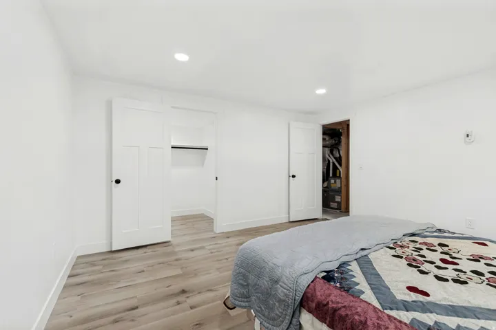 Recessed ceiling lighting, wood-finish flooring, white walls, and built-in closet with storage