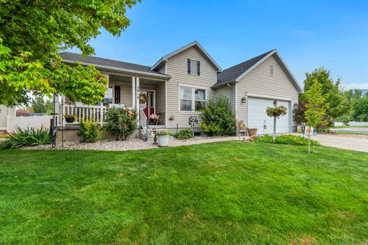 Siding exterior, attached garage, front porch, mature landscaping, and concrete driveway