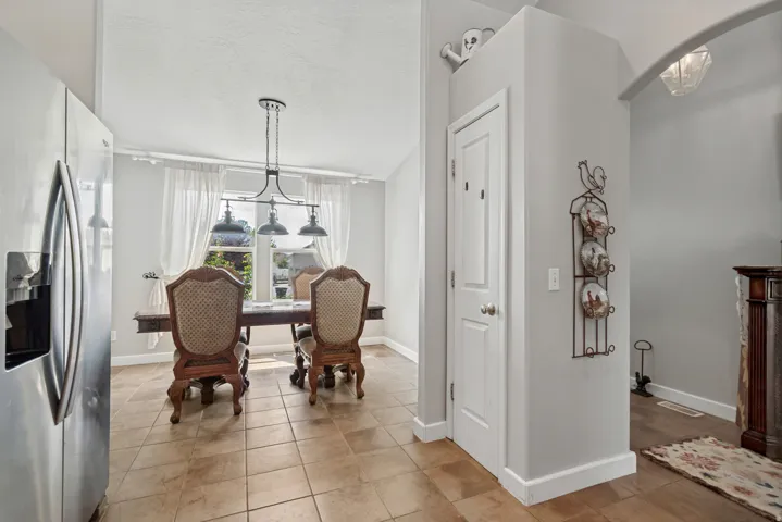 Stainless steel refrigerator, tile flooring, arched entry, and a window with natural light