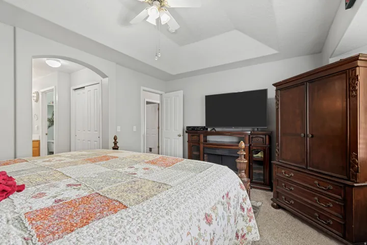 Arched doorway, ceiling fan, tray ceiling, carpet flooring, interior doors