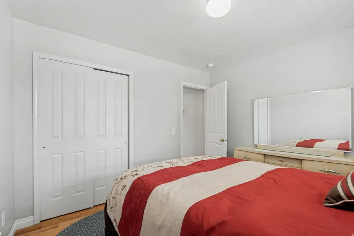 Wood-finish flooring with white baseboards, a white flush-mount ceiling light, and white paneled bi-fold closet doors