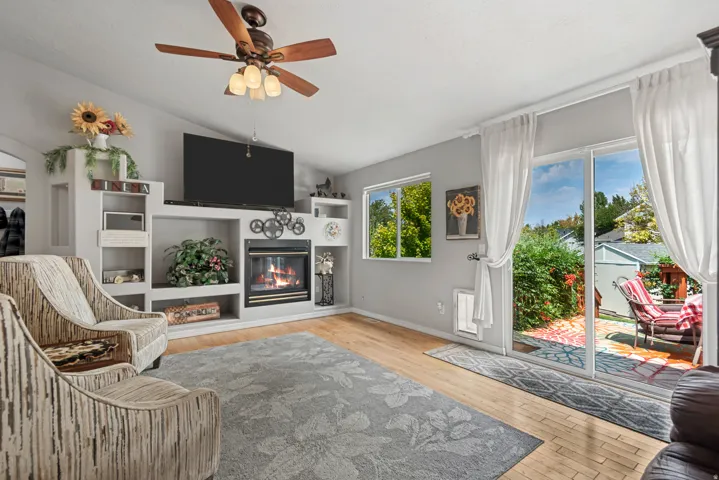 Vaulted ceiling with a ceiling fan, built-in entertainment center with a fireplace, and wood-finish flooring