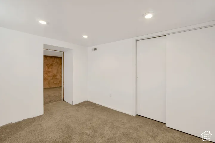 Recessed lighting, white walls, carpeted flooring, and a sliding closet door