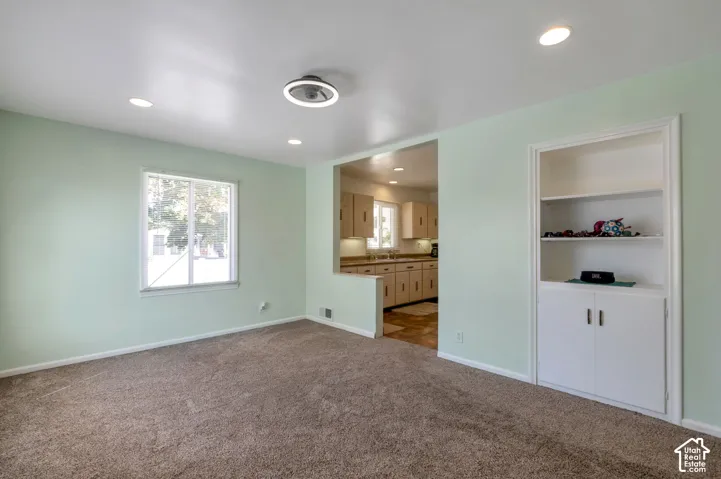 Family room leading into the kitchen.Recessed lighting, built-in shelving, built-in cabinetry, and a window with natural light
