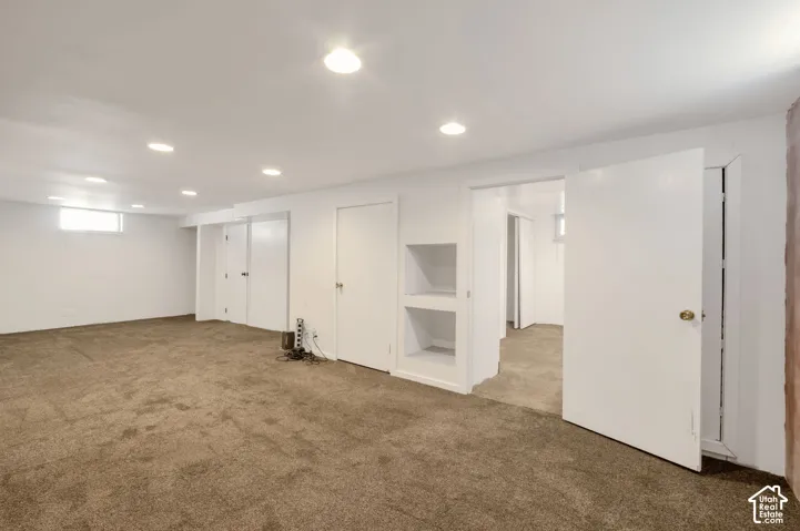 Huge finished lower level with recessed lighting, integrated shelving, and multiple white panel doors