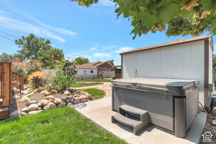 Outdoor spa with integrated steps, adjacent storage shed, and surrounding concrete patio